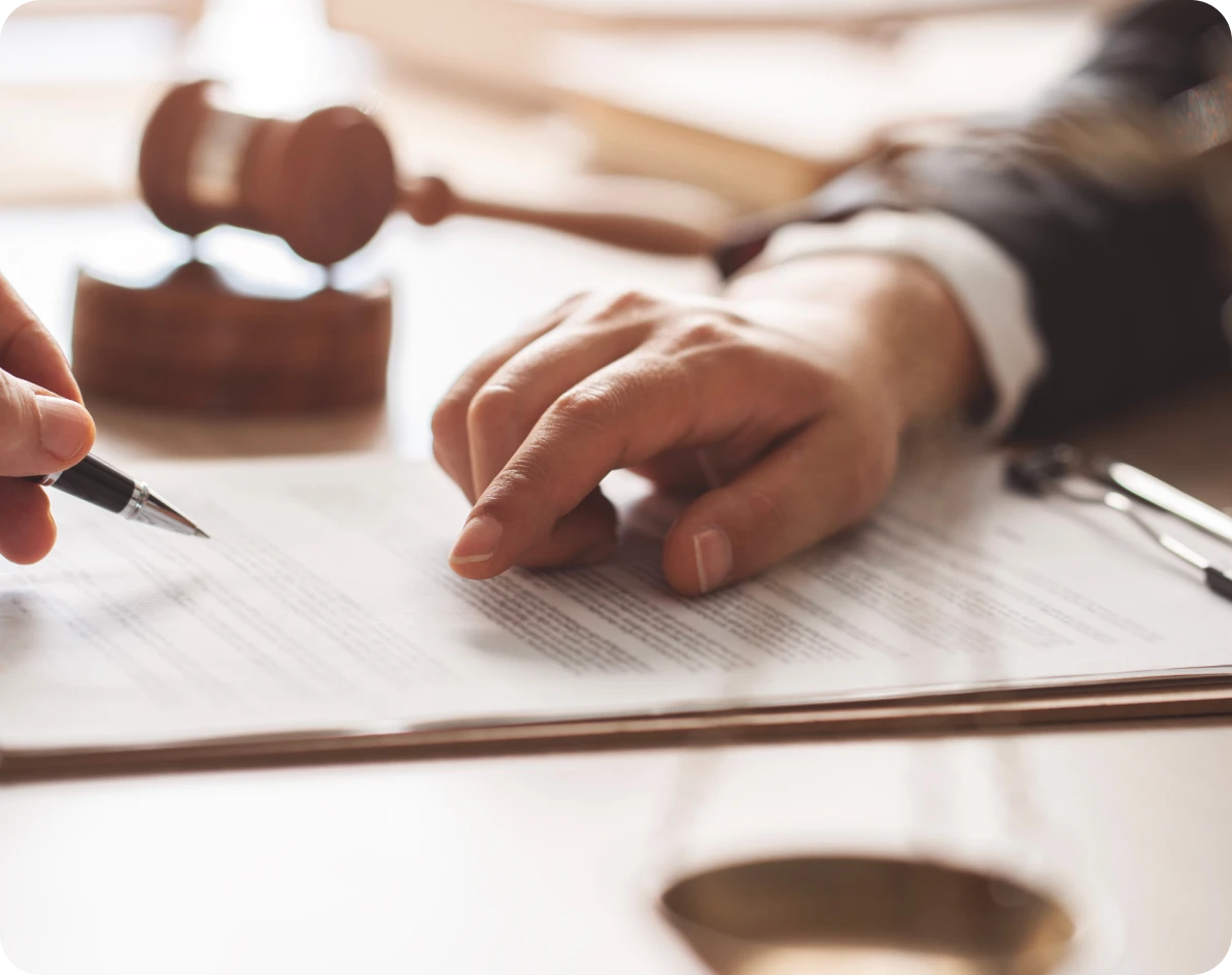 Signing legal document with gavel nearby.