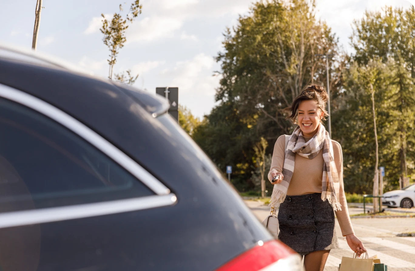 Woman approaching car with shopping bags.